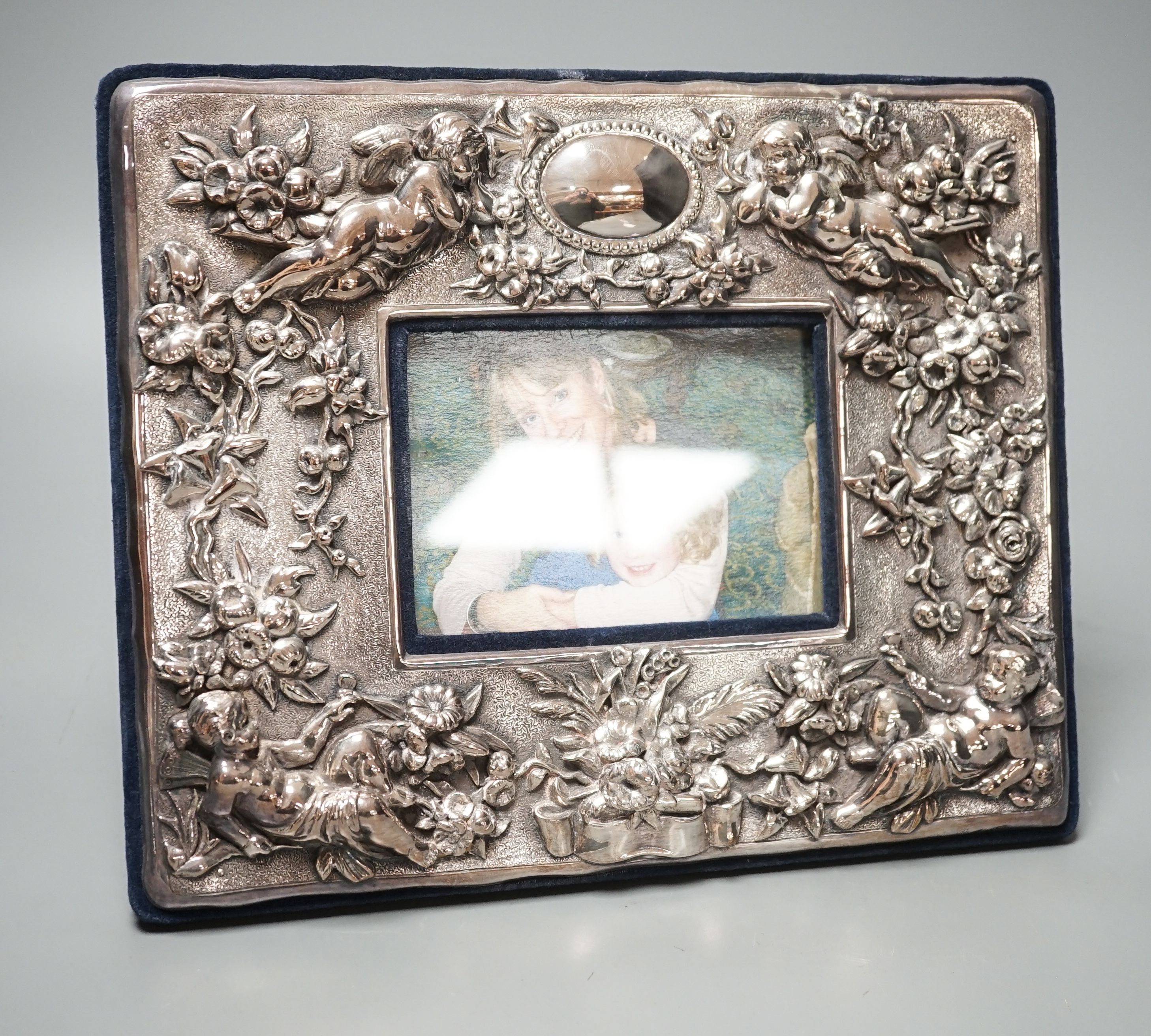 A modern sterling mounted photograph frame boldly embossed with cherubs, width 27.2cm.